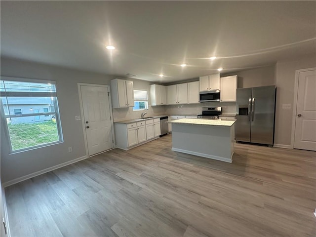 11045 Shadow Creek Ter, Hampton, GA 30228 - kitchen featuring stainless steel appliances, a sink, white cabinetry, light countertops, and light wood finished floors