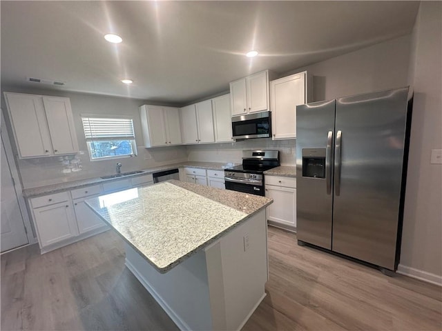 11045 Shadow Creek Ter, Hampton, GA 30228 - kitchen featuring stainless steel appliances, a sink, white cabinetry, light wood finished floors, and a kitchen island