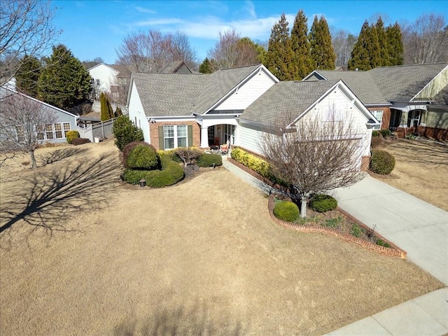 view of front facade featuring concrete driveway, brick siding, and roof with shingles