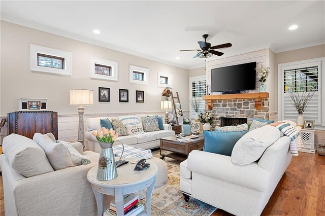 living area featuring a fireplace, recessed lighting, wood finished floors, and ornamental molding