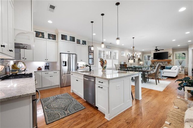 kitchen featuring light wood finished floors, visible vents, stainless steel appliances, white cabinetry, and a sink