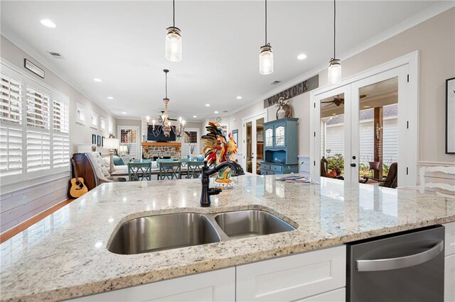 kitchen featuring a sink, stainless steel dishwasher, open floor plan, and ornamental molding