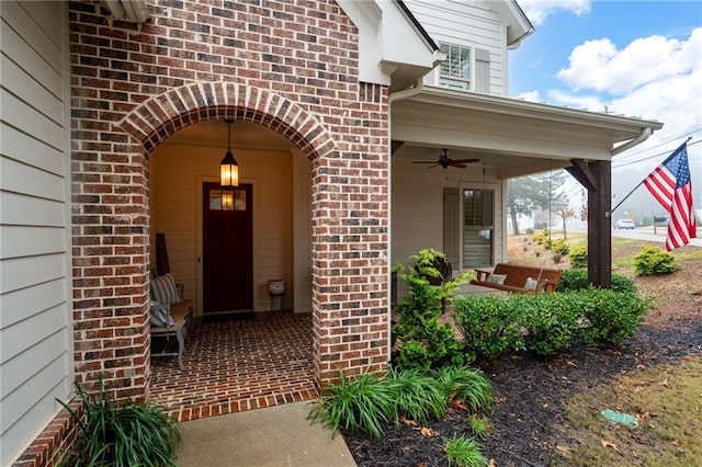 doorway to property with a ceiling fan, covered porch, and brick siding