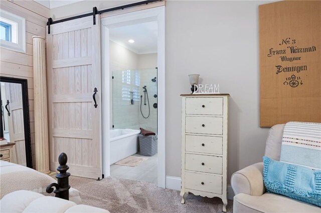 bedroom with a barn door, ensuite bathroom, and carpet floors