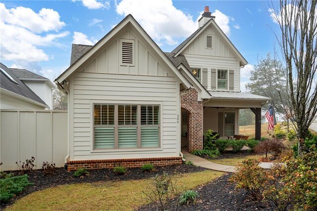 rear view of property featuring board and batten siding and fence