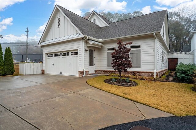 view of front of property with fence, roof with shingles, board and batten siding, concrete driveway, and an attached garage