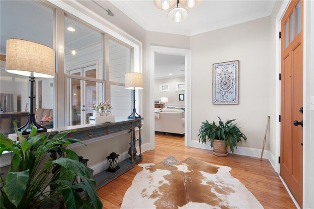 entryway with baseboards, wood finished floors, and ornamental molding