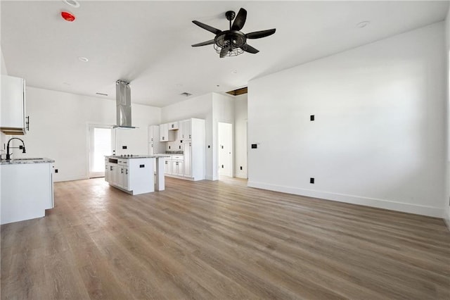 unfurnished living room featuring sink, wood-type flooring, and ceiling fan