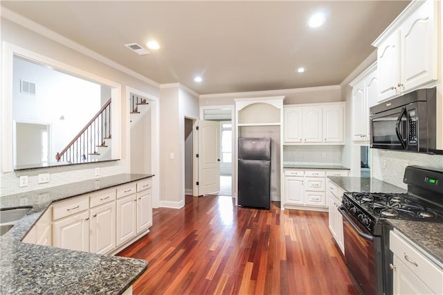 kitchen featuring dark stone countertops, white cabinetry, and black appliances