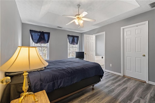 bedroom featuring a textured ceiling, wood finished floors, visible vents, and baseboards