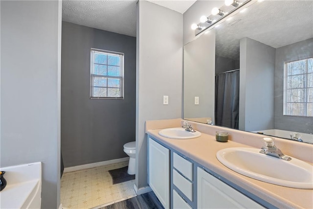 full bathroom with toilet, plenty of natural light, a sink, and tile patterned floors