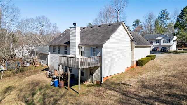 rear view of property with a yard, a chimney, a wooden deck, and a residential view