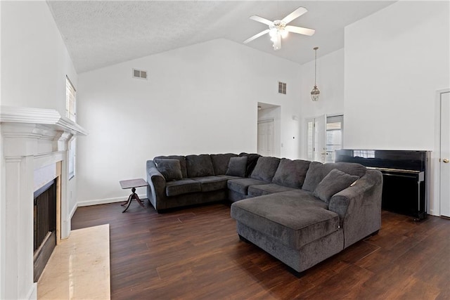 living area with dark wood-type flooring, a high end fireplace, visible vents, and ceiling fan