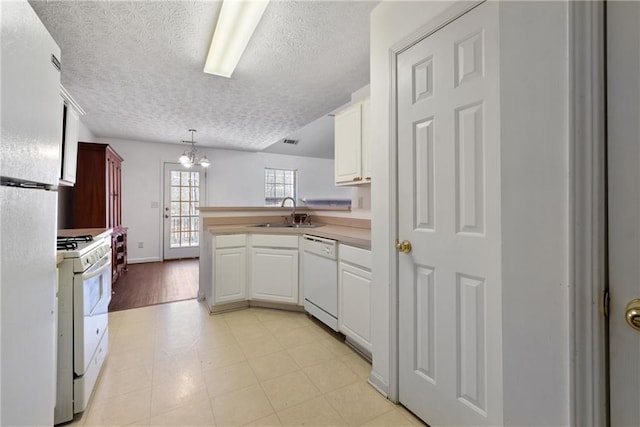 kitchen featuring a peninsula, white appliances, white cabinets, and a sink