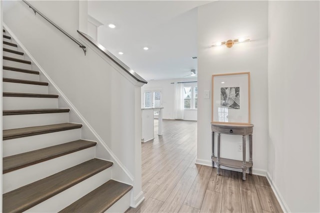 stairs featuring ceiling fan and wood-type flooring