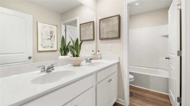 full bathroom featuring double vanity, washtub / shower combination, wood-type flooring, and toilet