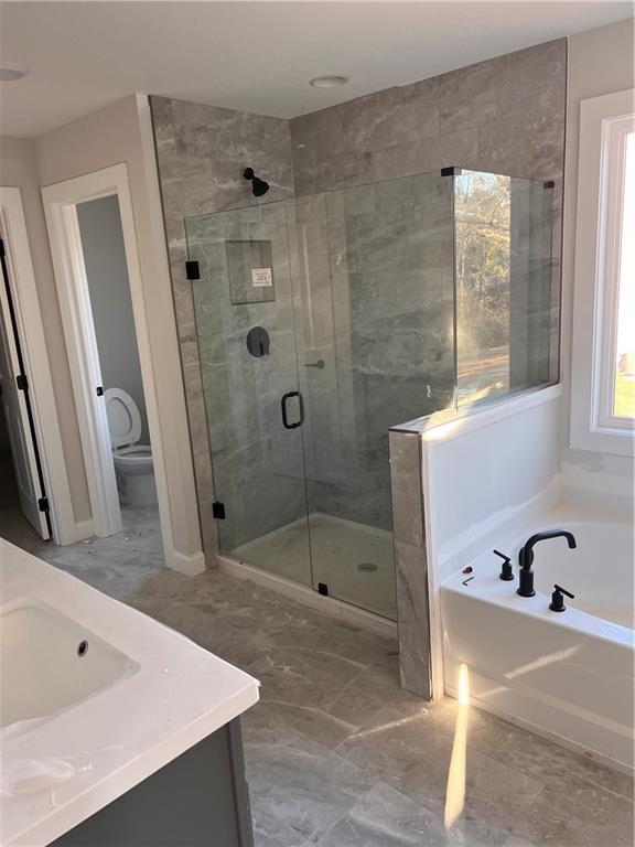 full bathroom featuring toilet, vanity, and separate shower and tub