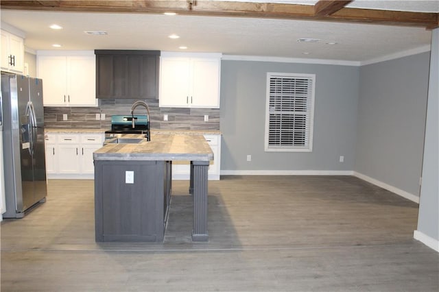 kitchen with light stone counters, tasteful backsplash, an island with sink, stainless steel appliances, and white cabinets