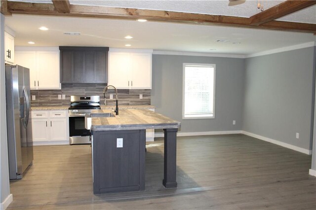 kitchen featuring tasteful backsplash, stainless steel appliances, light wood-style floors, white cabinetry, and a sink