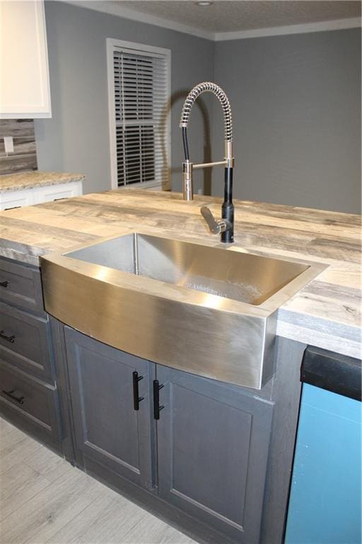 details with sink, crown molding, butcher block counters, backsplash, and white cabinets