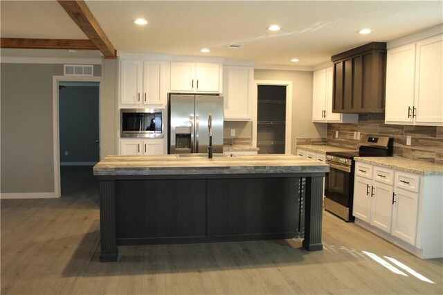 kitchen with white cabinets, an island with sink, stainless steel appliances, light countertops, and a sink