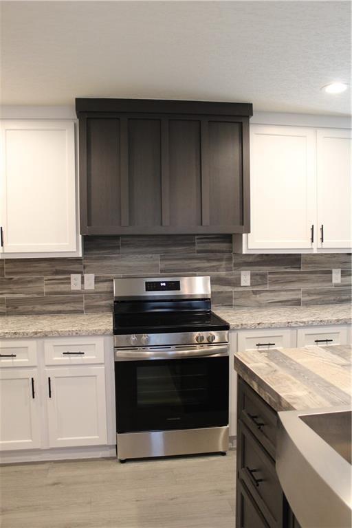 kitchen with stainless steel fridge, white cabinetry, light countertops, and wood finished floors