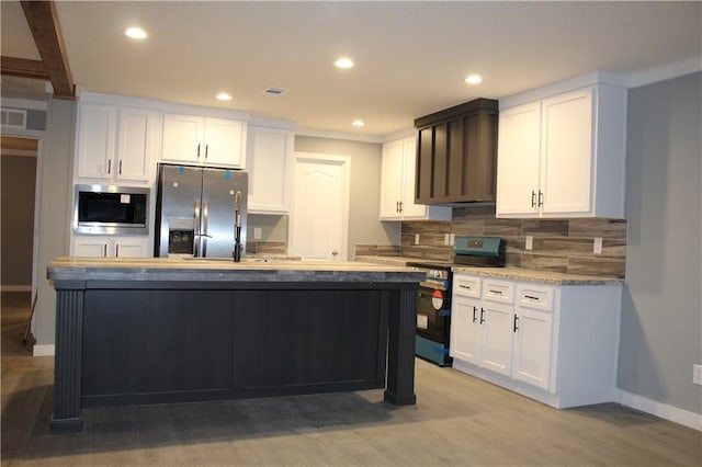 kitchen with decorative backsplash, appliances with stainless steel finishes, a center island with sink, and white cabinets