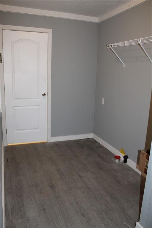 empty room featuring baseboards, a textured ceiling, a ceiling fan, and dark wood-style flooring