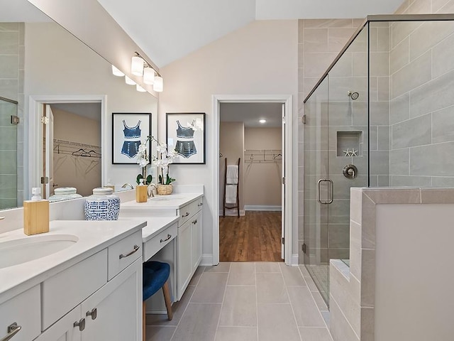 bathroom with tile patterned flooring, vanity, a shower with shower door, and vaulted ceiling