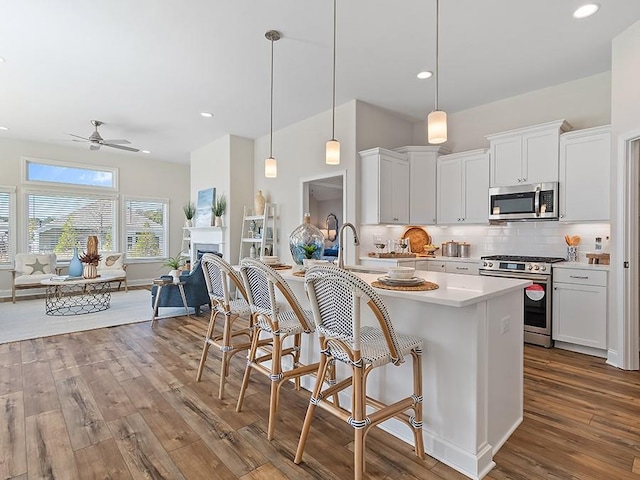 kitchen featuring pendant lighting, white cabinets, dark wood-type flooring, and appliances with stainless steel finishes