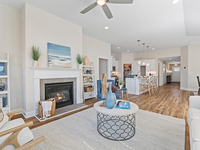 living room featuring hardwood / wood-style floors, ceiling fan, and sink