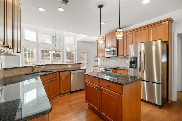 kitchen with appliances with stainless steel finishes, a center island, pendant lighting, and sink