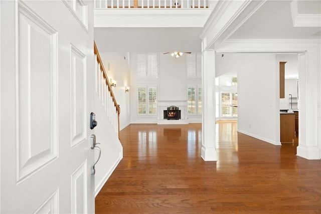 foyer with crown molding, a towering ceiling, dark hardwood / wood-style floors, and a wealth of natural light