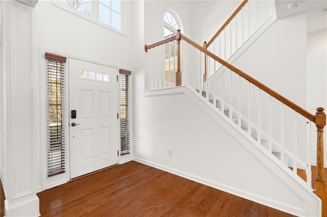 entrance foyer with a towering ceiling, plenty of natural light, and dark hardwood / wood-style floors