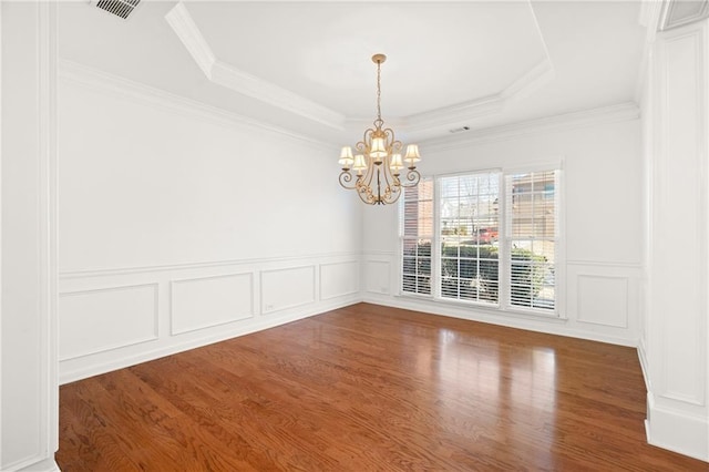 unfurnished dining area featuring a notable chandelier, hardwood / wood-style flooring, ornamental molding, and a raised ceiling