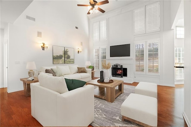 living room with a towering ceiling, wood-type flooring, and ceiling fan