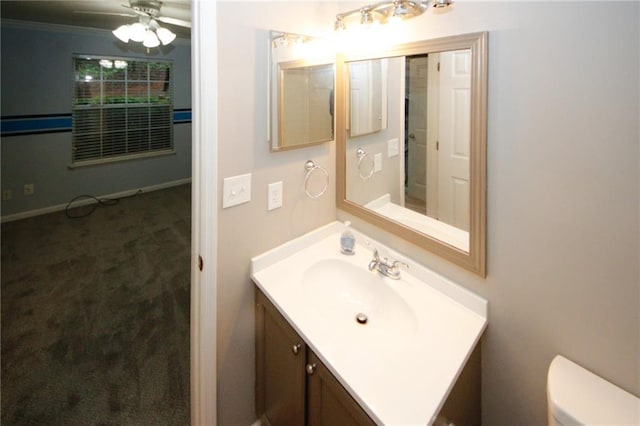 bathroom with ceiling fan, vanity, toilet, and baseboards