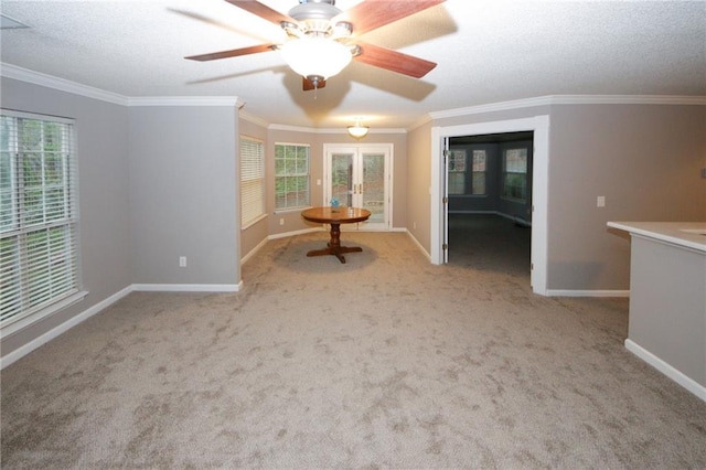 unfurnished room with baseboards, french doors, carpet, a textured ceiling, and crown molding