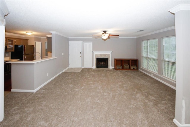 unfurnished living room featuring light carpet, a premium fireplace, a ceiling fan, and crown molding