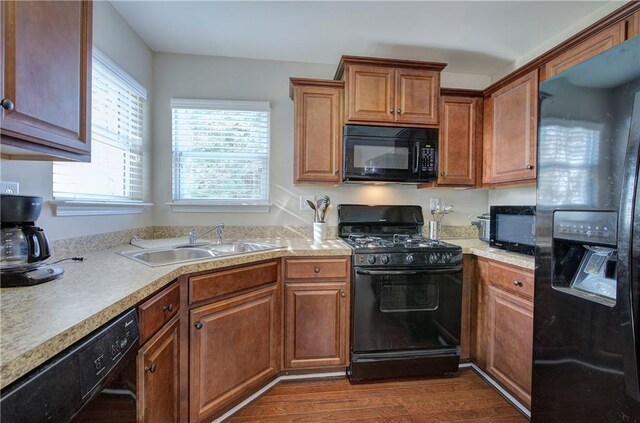 kitchen with black appliances, hardwood / wood-style floors, and sink