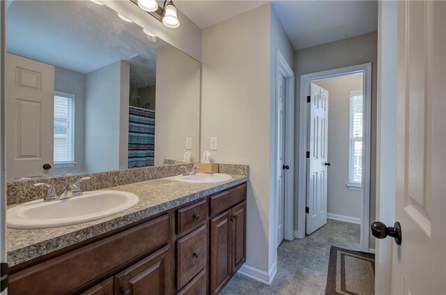 bedroom with ceiling fan, light colored carpet, ensuite bathroom, and a raised ceiling