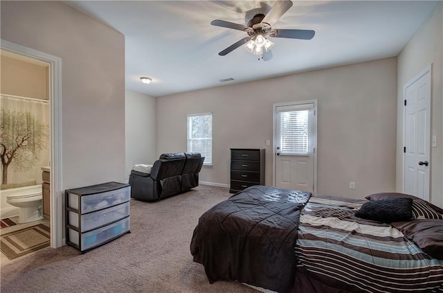 bedroom with ensuite bath, light colored carpet, and ceiling fan