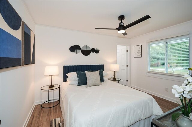 bedroom with hardwood / wood-style flooring, ceiling fan, and ornamental molding