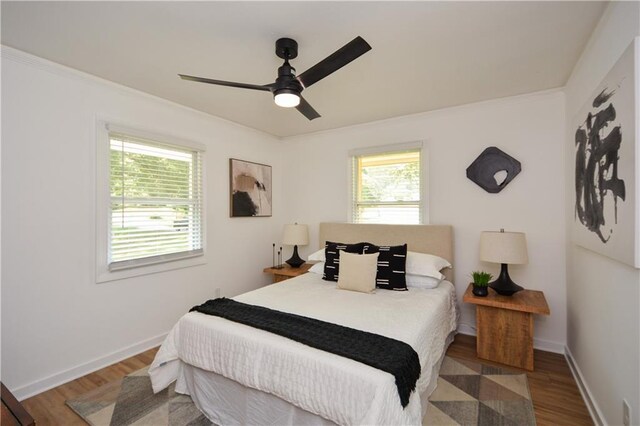 bedroom featuring dark hardwood / wood-style flooring, ceiling fan, and crown molding