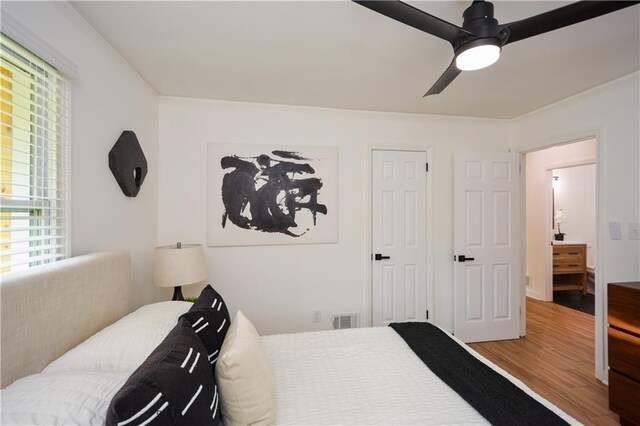 bedroom with multiple windows, hardwood / wood-style flooring, ceiling fan, and crown molding