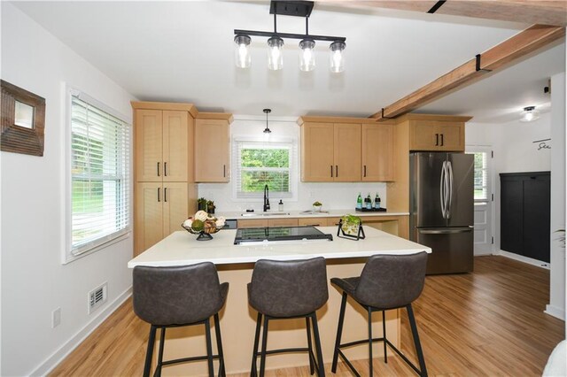 kitchen featuring decorative light fixtures, light brown cabinets, sink, and appliances with stainless steel finishes