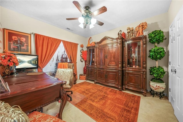 office area with visible vents, light colored carpet, and a ceiling fan