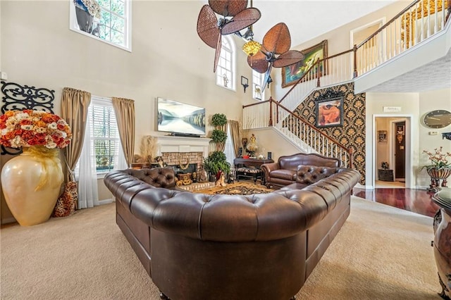 living room featuring stairway, carpet, baseboards, a fireplace, and a towering ceiling