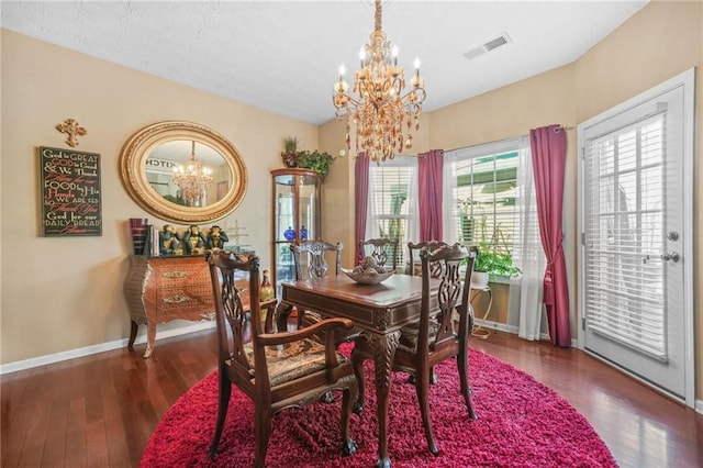 dining room featuring hardwood / wood-style floors, a notable chandelier, baseboards, and visible vents