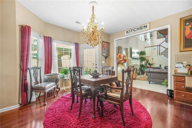 dining space featuring a chandelier, visible vents, baseboards, and wood finished floors